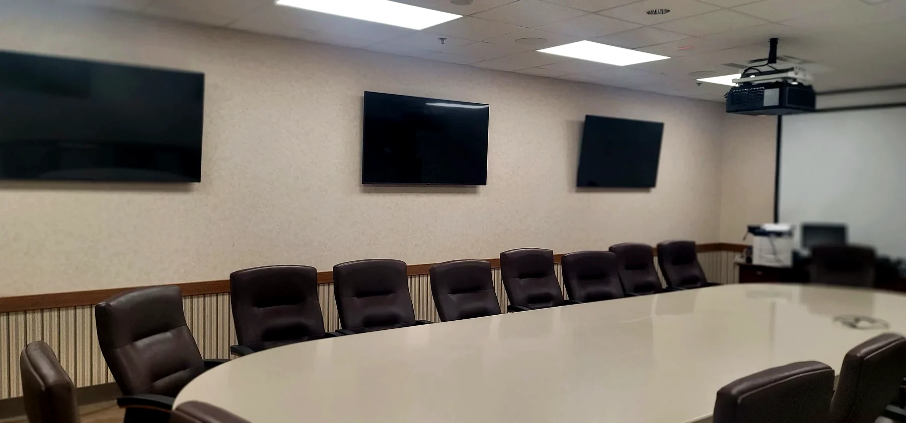 Commercial boardroom AV installation with multiple wall mounted displays and conference table