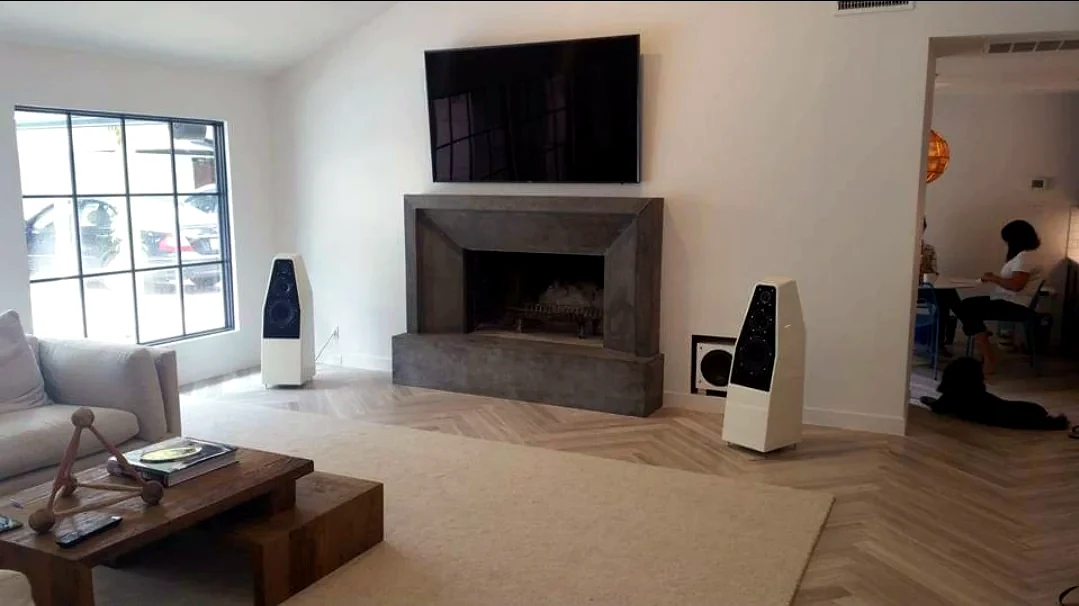 Modern residential living room with television fireplace and white floorstanding speakers